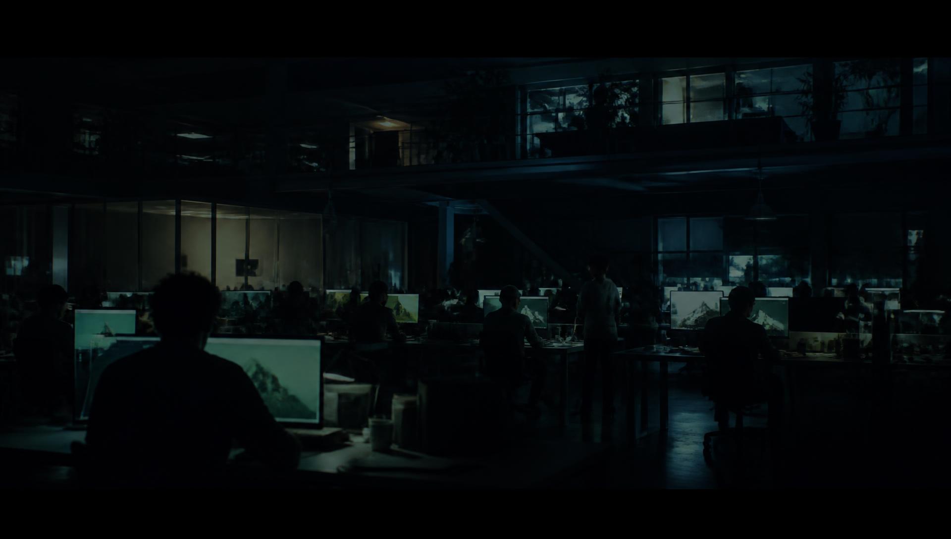 A larger, busier studio office at night with many glowing monitors